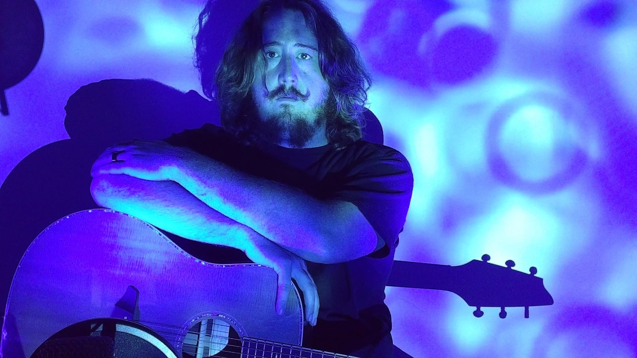 Musician Cody the Sentinel holds a guitar